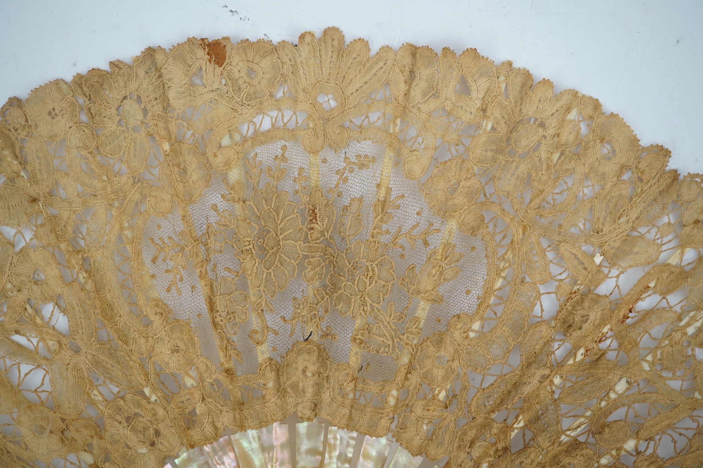 Three novelty fans with a mixed Brussels lace fan and black lace fan, a small language of love in flowers fan, a paper windmill advertising French Café fan, a carved cream Bakelite fan, a black and gilt, lace and sequin